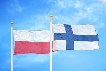 Poland and Finland two flags on flagpoles and blue cloudy sky