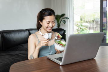 A young Asian woman using a computer in the living room