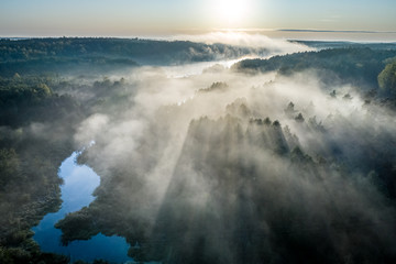 Fog over river with rays in autumn, aerial view