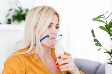 Young woman using nebulizer for asthma and respiratory diseases at home