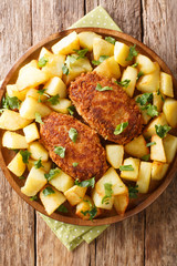 Russian Pozharsky cutlets with a side dish of fried potatoes close-up in a plate. vertical top view
