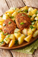 Russian Pozharsky cutlets with a side dish of fried potatoes close-up in a plate. vertical