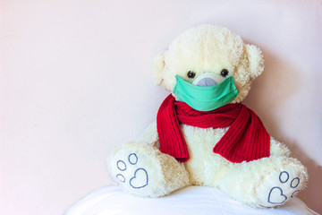 Soft toy teddy bear in a medical mask and scarf, the concept of quarantine and self-isolation from the coronavirus virus and other diseases