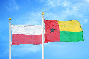 Poland and Guinea-Bissau two flags on flagpoles and blue cloudy sky