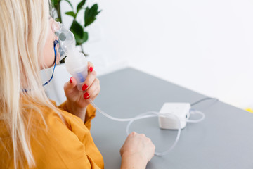 Portrait of adult woman using steam vapor inhaler nebulizer doing aerosol inhalation medicine...