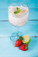 Strawberry cocktail or milkshake in a glass on a blue rustic background