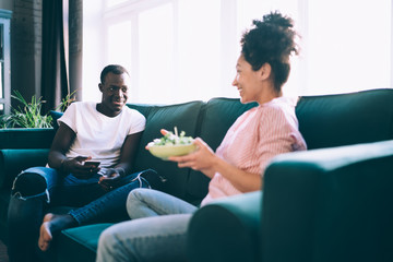 Diverse happy couple talking and relaxing on sofa