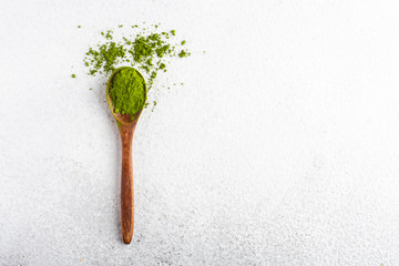 wooden spoon with matcha tea green powder on white background