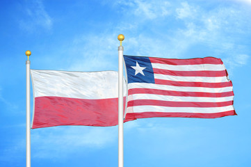 Poland and Liberia two flags on flagpoles and blue cloudy sky