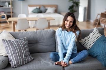 Obraz premium Pretty woman relaxing on the couch at home in the living room.