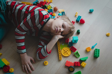 kid tired of playing, exhaustion with toys scattered around, staying home difficulty