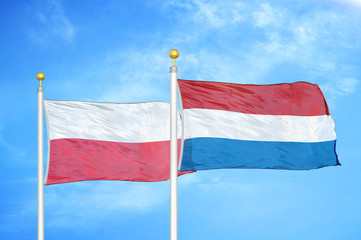 Poland and Netherlands two flags on flagpoles and blue cloudy sky