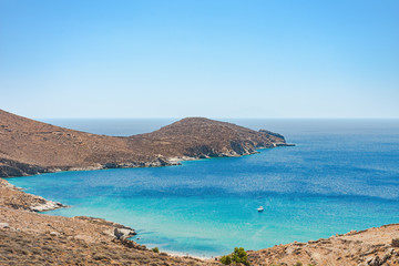 An isolated beach with turquoise water and a yacht in Serifos island Cyclades Aegean Greece on a sunny summer day