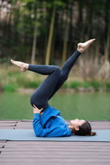 Fototapeta na wymiar A young Asian woman doing yoga by the lake