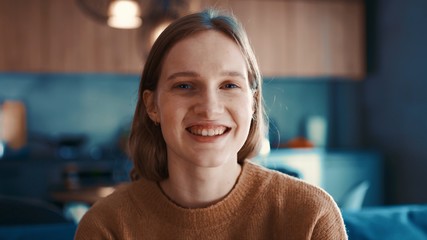Portrait of happy attractive girl with blonde hair in brown sweater loking to the camera and smiling. Close-up - obrazy, fototapety, plakaty