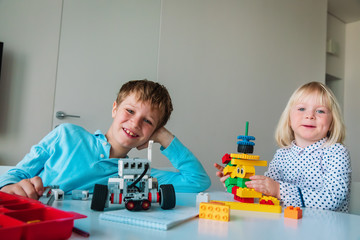 little girl and boy building robots from colorful plastic blocks