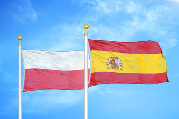 Poland and Spain two flags on flagpoles and blue cloudy sky