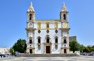 Faro / Algarve, Portugal - Church of Carmo, a white building with yellow décor, steps in front of...