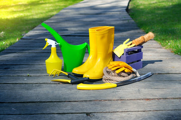 Gardening. Rain boots and garden work tools on the wooden terrace.