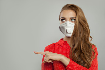 Woman in medical mask pointing finger and looking aside on white