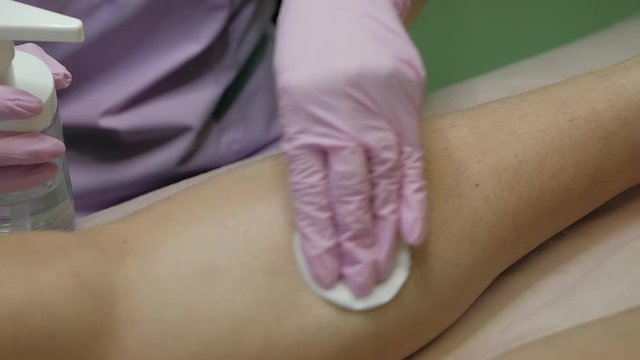 Hair removal specialist prepares woman's skin for the epilation procedure. 