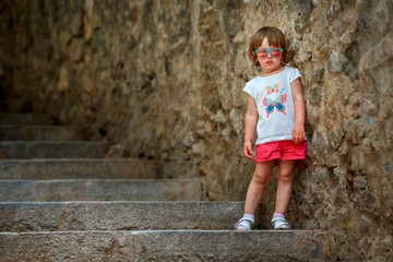 Cute curly toddler girl walking in famous ancient medieval city Girona, Catalonia, Spain