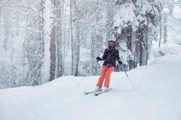 Fototapeta na wymiar Young woman skiing under snowfall