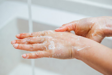 Close-up of woman washing hands with a soap.