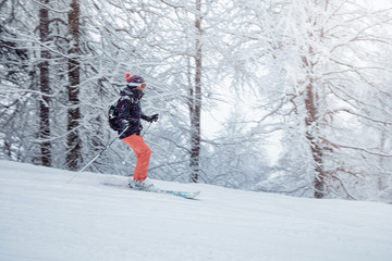 Naklejka na ściany i meble Young woman skiing under snowfall