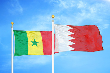 Senegal and Bahrain  two flags on flagpoles and blue cloudy sky