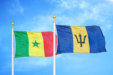 Senegal and Barbados  two flags on flagpoles and blue cloudy sky