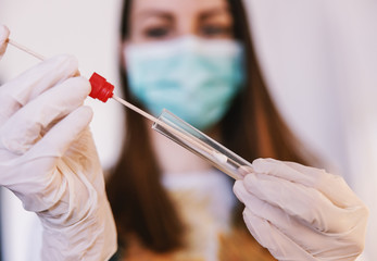 Close up of young woman with sample swab. Selective focus on sample. Corona virus protective...