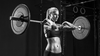 Fototapeta na wymiar Barbell Workout Indoor shot of caucasian female doing exercise with barbell Blonde woman crossfit workout in gym. Female performing deadlift exercise with weight bar Concept black and white photo.