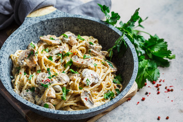 Creamy mushroom spaghetti pasta with parsley in gray pan, gray background.