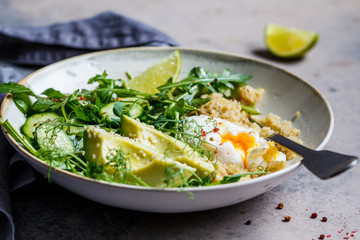 Quinoa salad with egg and avocado in gray bowl, gray background. Paleo diet menu concept.