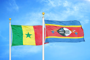 Senegal and Eswatini Swaziland two flags on flagpoles and blue cloudy sky