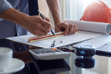 Architect man or male engineer work on architectural project with laptop computer, calculator and...