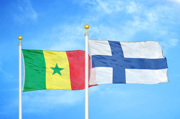 Senegal and Finland two flags on flagpoles and blue cloudy sky