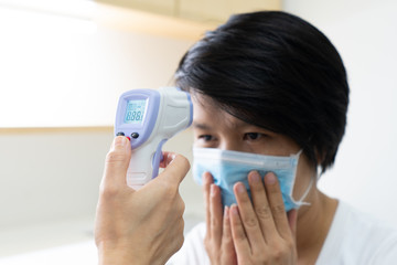 A nurse using a digital thermometer to measure temperature of a woman patient that gets sick. covid-19, coronavirus, medical, healthcare, fever concept