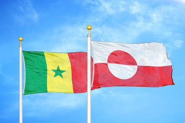 Senegal and Greenland two flags on flagpoles and blue cloudy sky