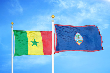 Senegal and Guam two flags on flagpoles and blue cloudy sky