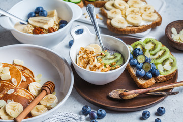 Healthy vegan breakfast table. Oatmeal with fruits, chia pudding, pancakes and toasts with fruits, vegetables and cream cheese.