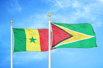 Senegal and Guyana two flags on flagpoles and blue cloudy sky