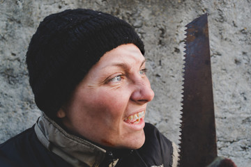 Homeless woman with a saw in her hands