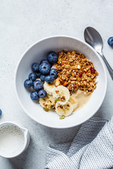 Granola with berries and fruits in a white bowl on a gray background. Healthy breakfast concept.