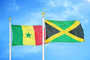 Senegal and Jamaica two flags on flagpoles and blue cloudy sky