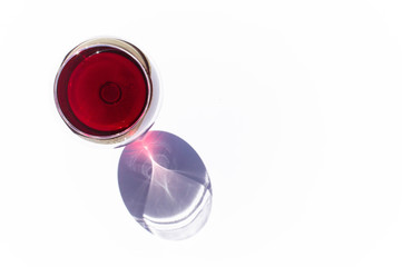 A glass of pink red wine on white background with sparkling shadows. Top view. Free copy space.  Concept of organic drinks.