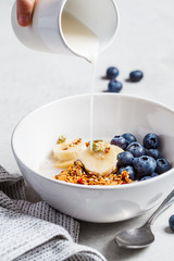 Granola with milk, berries and fruits in a white bowl. Healthy breakfast concept.