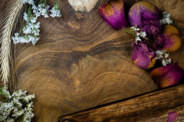 Zdjęcie drewnianej deski z góry, dookoła ususzone kwiaty.