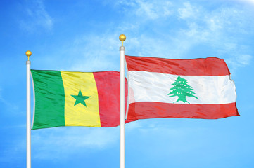 Senegal and Lebanon two flags on flagpoles and blue cloudy sky